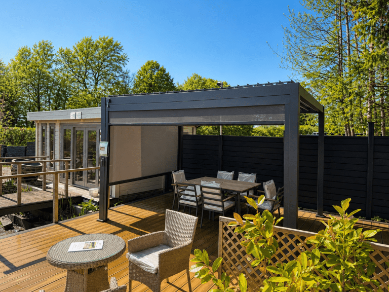 Wider view of the Nova Titan pergola display area at Carr Bank Garden Centre, showing the decking and pull-down side screen