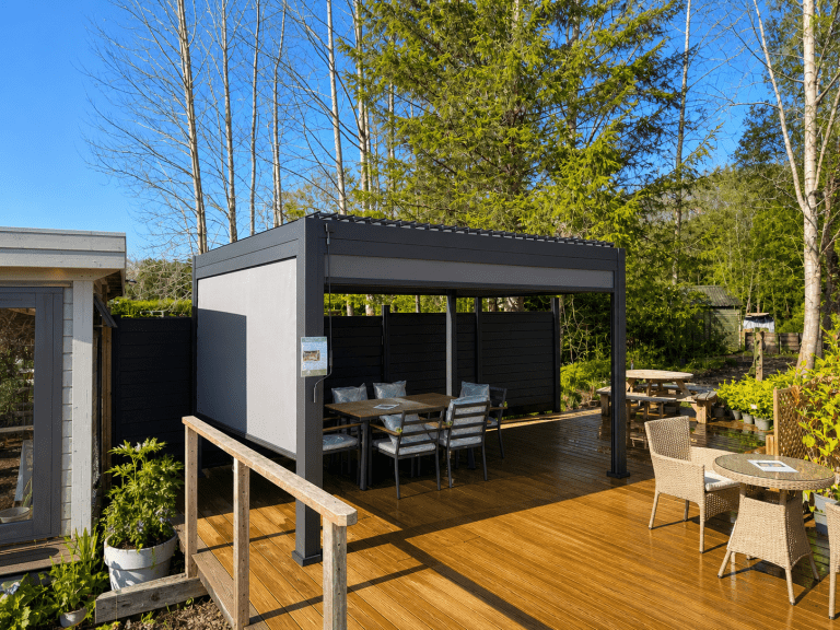 4m x 3m Nova Titan aluminium pergola on display at Carr Bank Garden Centre, with dining table and pull-down side screen